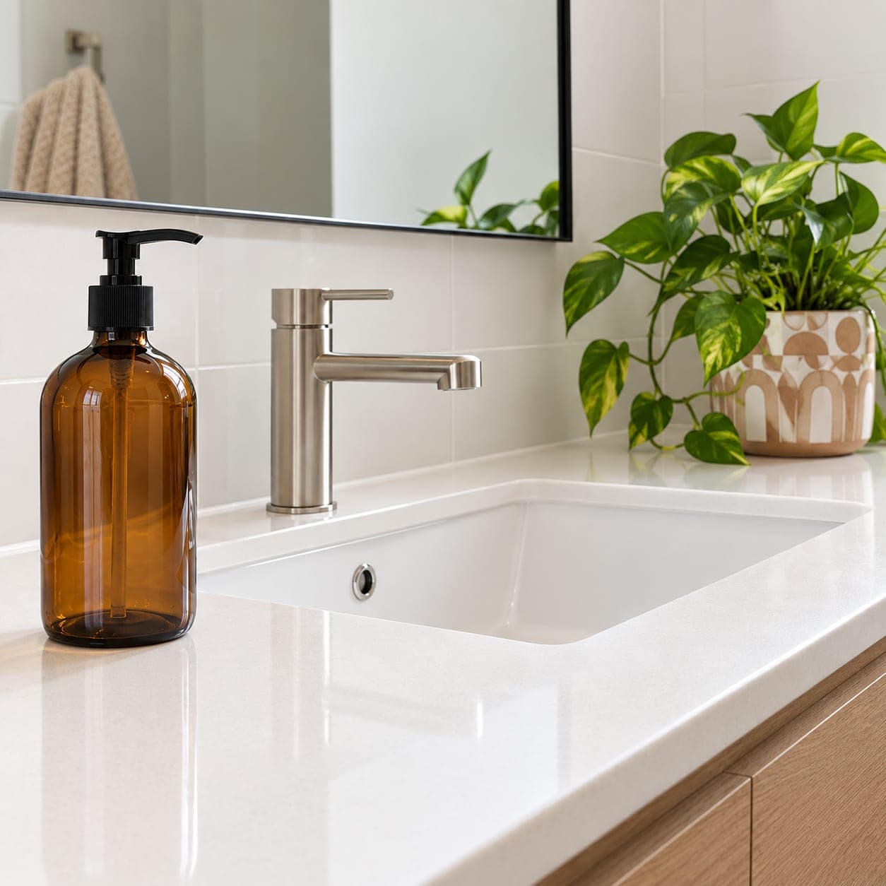 A brown glass pump bottle of hand soap on a bathroom vanity beside the sink.