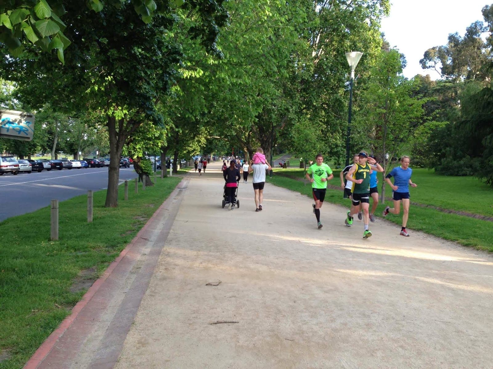 A group of runners in matching club singlets moving at pace along the Tan track, seen from behind.